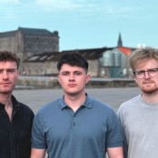 Three men stood against village background